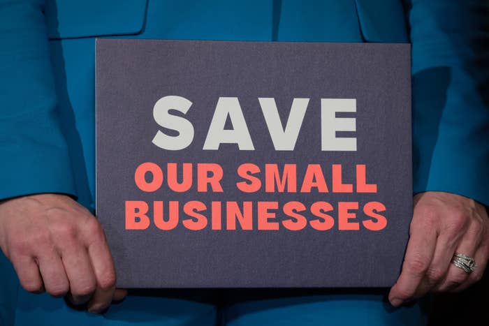 Person holds a sign reading "Save Our Small Businesses."