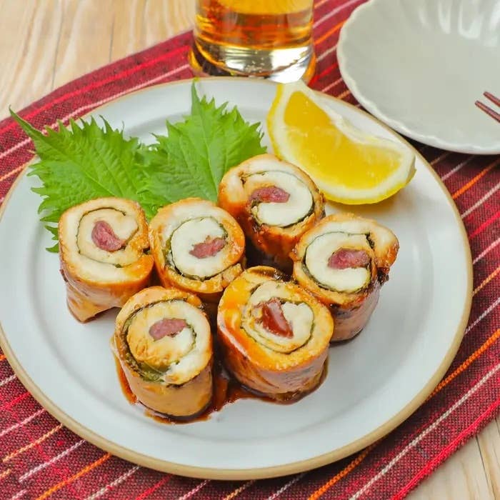 皿に盛られた野菜と肉が巻いてあるロール、レモン添え。ガラスの飲み物が後ろにある。