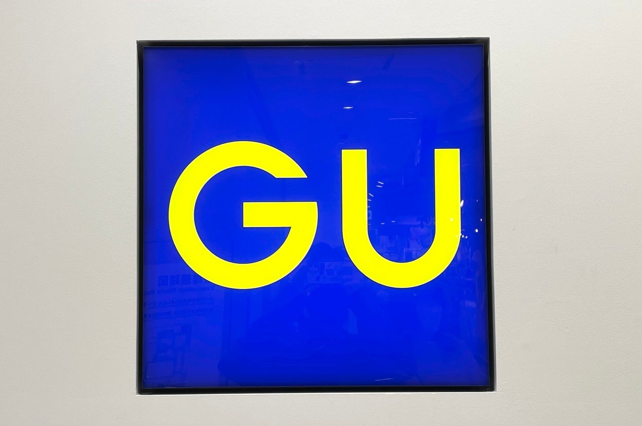 A square sign with the letters "GU" in bold, set against a plain background