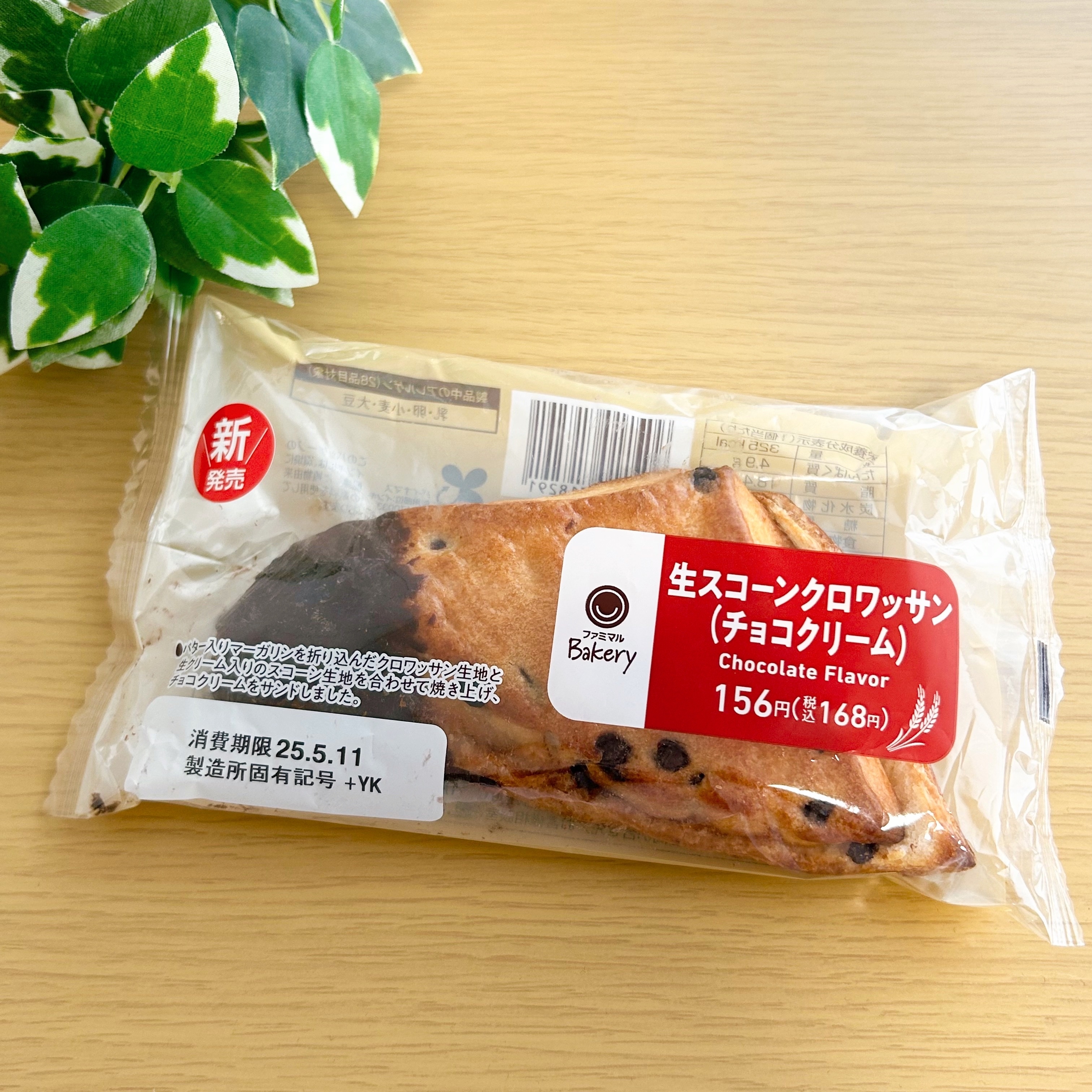 包装されたチョコレート味のクロワッサン。新商品ラベルがあり、緑の植物が横に置かれている。