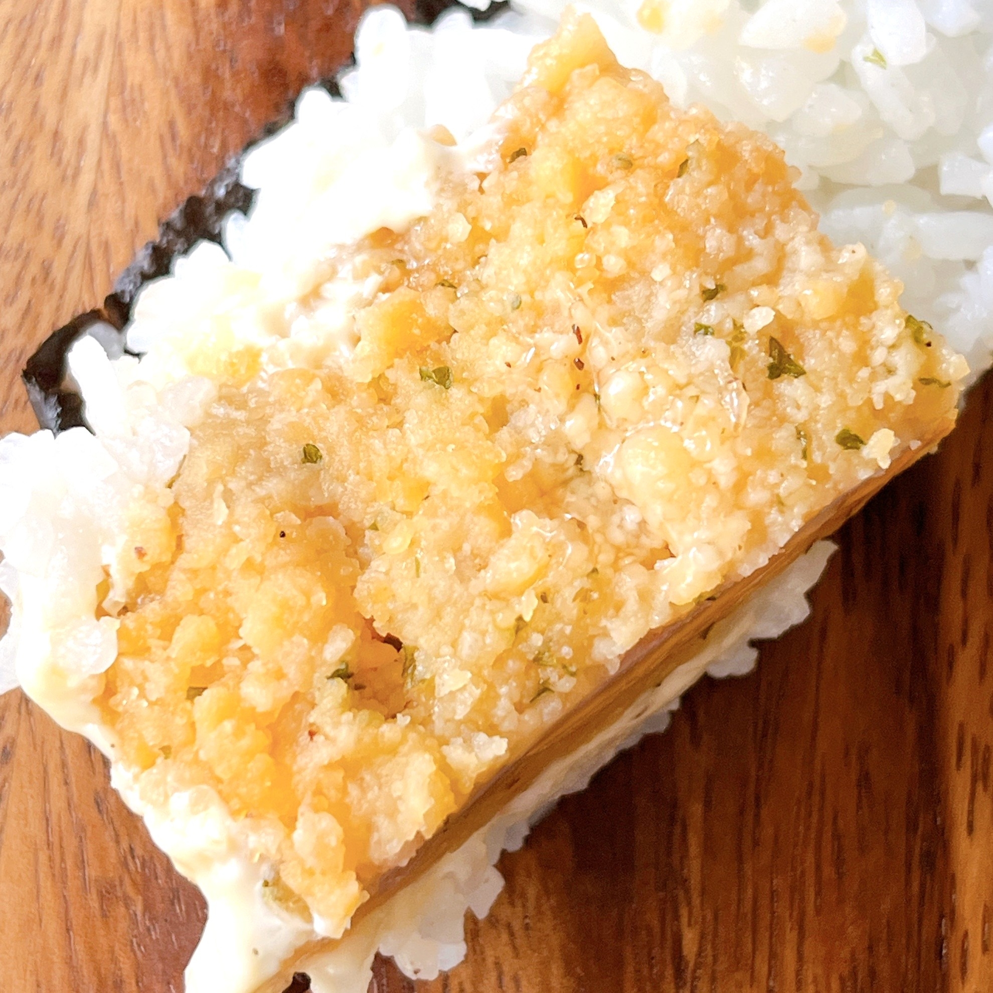 寿司のネタとして使用されたクリスピーな衣のある料理が白いご飯の上に乗っている。