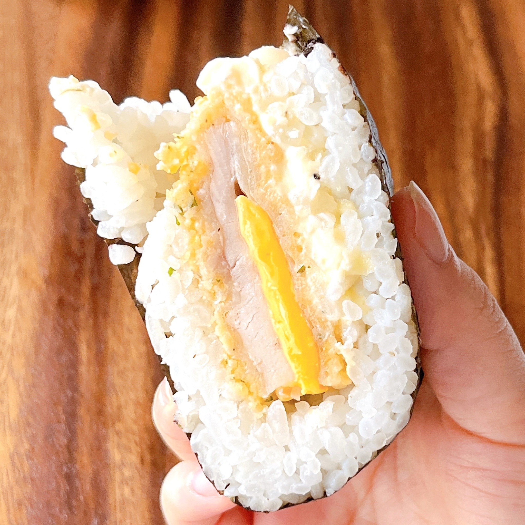 おにぎらずを手に持っている写真。中身にはスパム、卵、チーズが挟まれている。