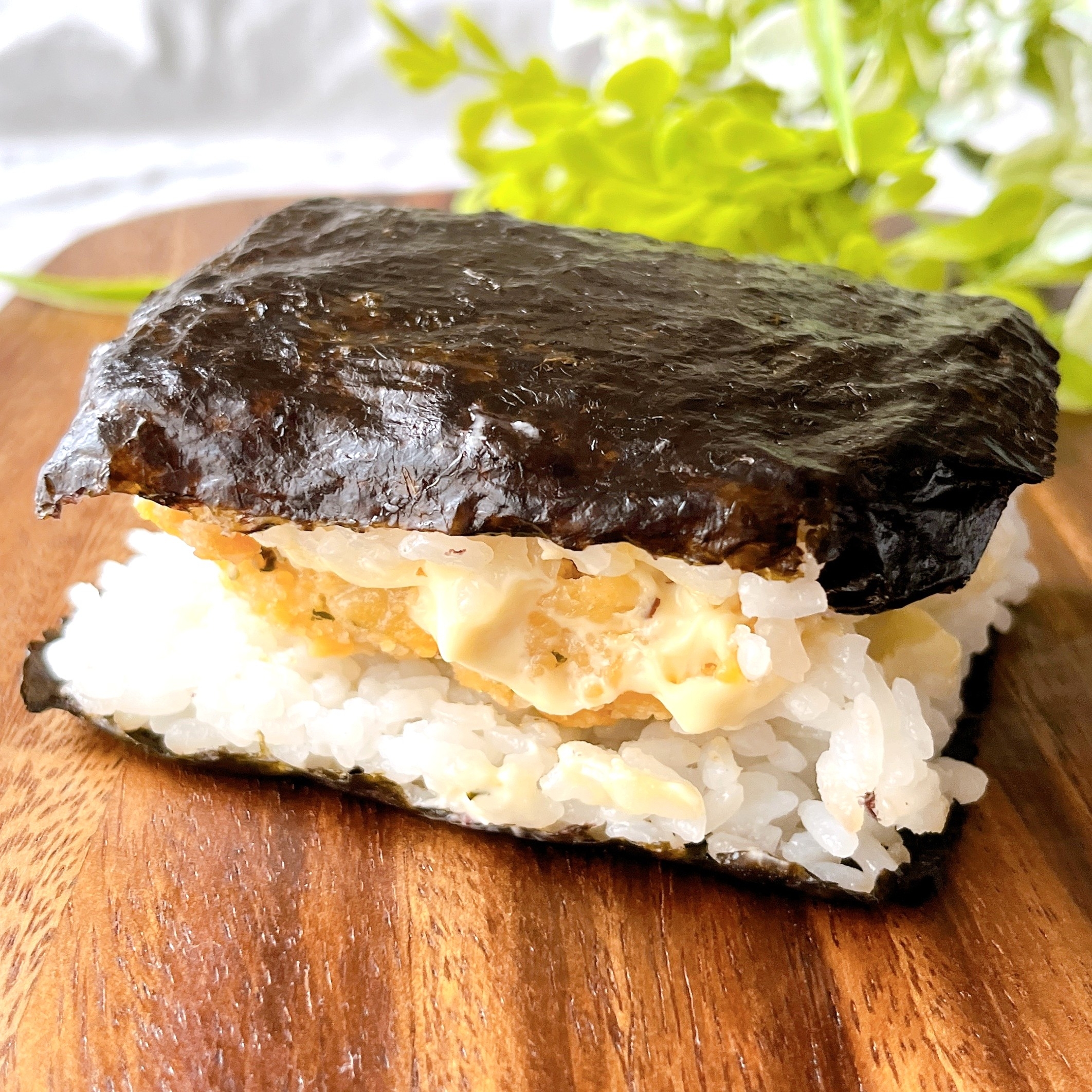 ご飯と卵の間に挟まれたのりを使ったおにぎらずが木製の板の上に置かれています。