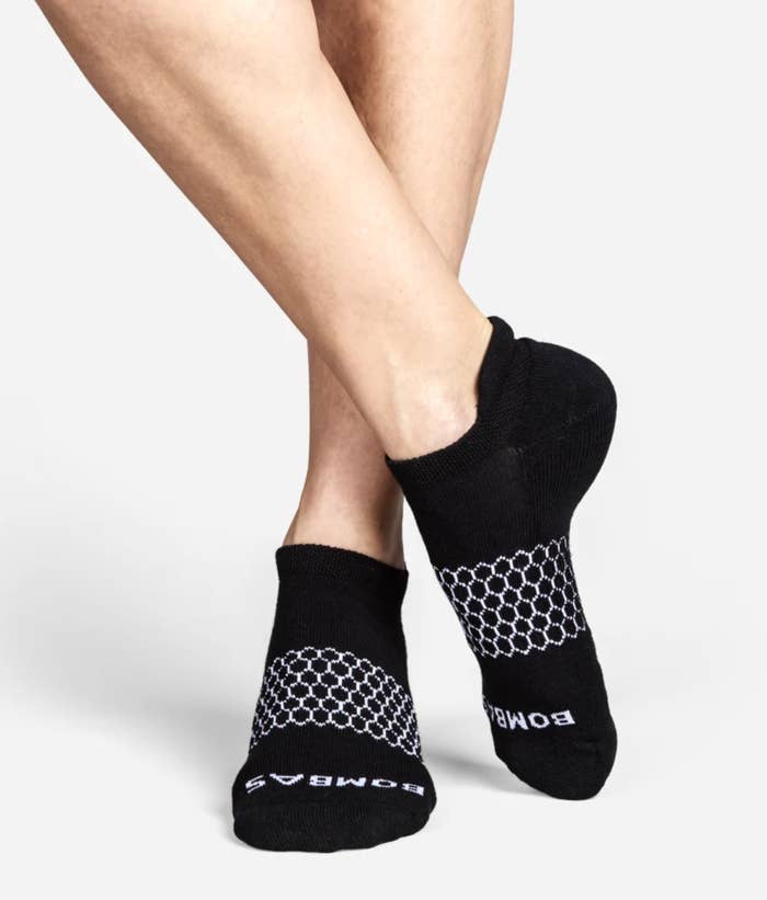 Model wearing achromatic ankle socks with achromatic detailing