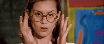 Person adjusting glasses, looking surprised, with abstract art in the background