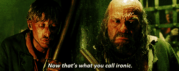 Two men from a movie scene; one is holding a club. Caption reads, "Now that's what you call ironic."