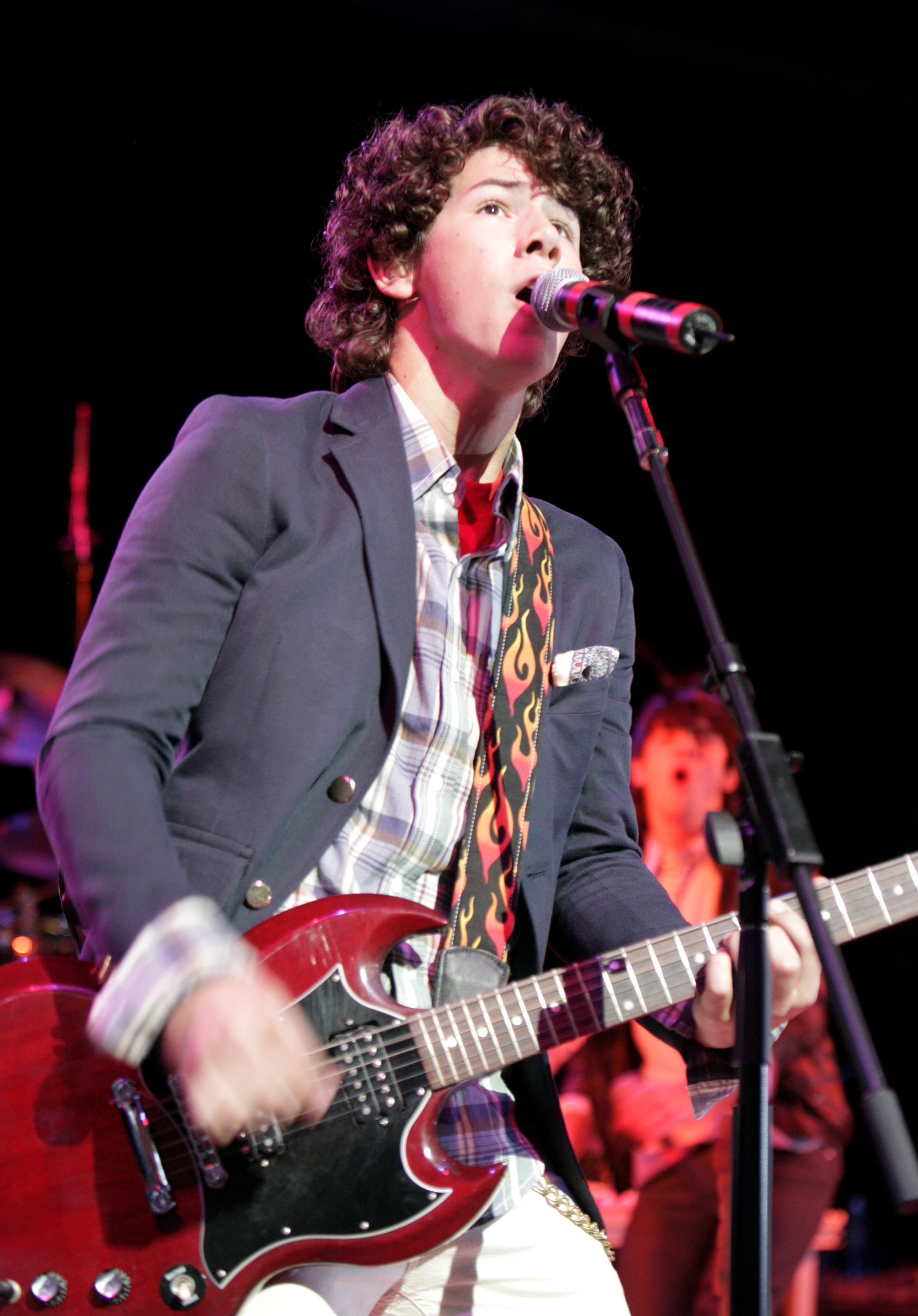 Young Nick Jonas playing an electric guitar on stage