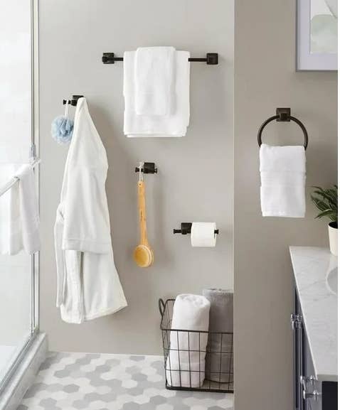Bathroom with towel racks, a robe, a ablution brush, toilet paper, and a ligament basket. Geometric tile level and partial ablution view