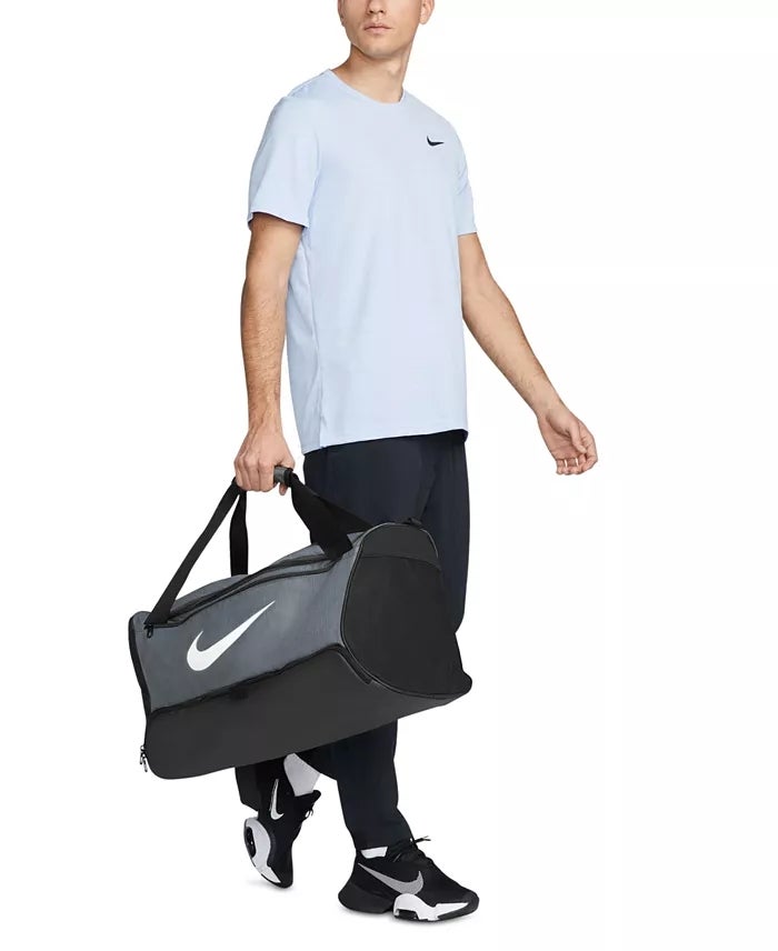 Orang yang mengenakan pakaian atletik kasual memegang tas ransel nike
