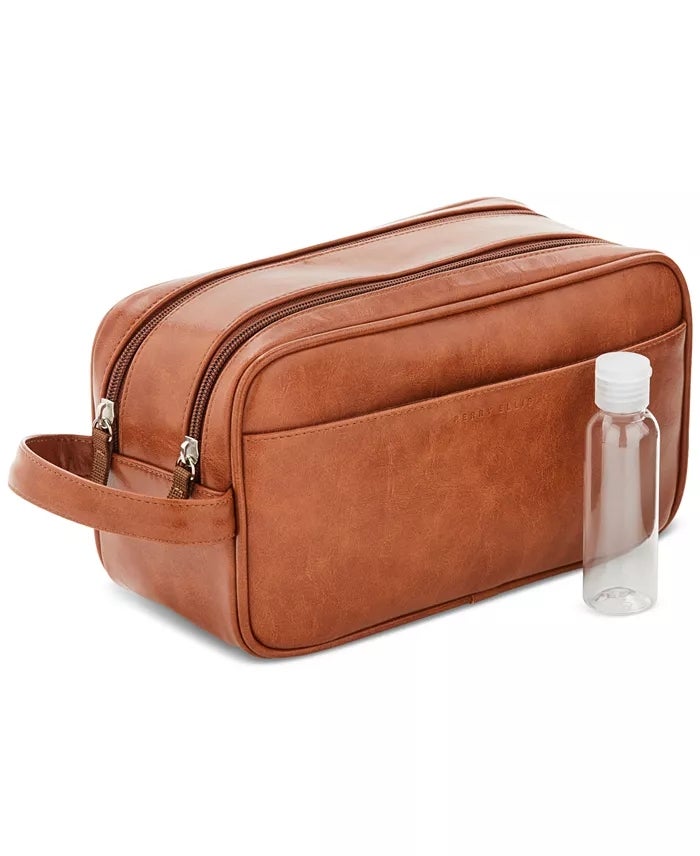 Tas perlengkapan mandi kulit coklat dengan ritsleting ganda dan botol plastik bening di sampingnya. Ideal untuk perjalanan atau penyimpanan terorganisir