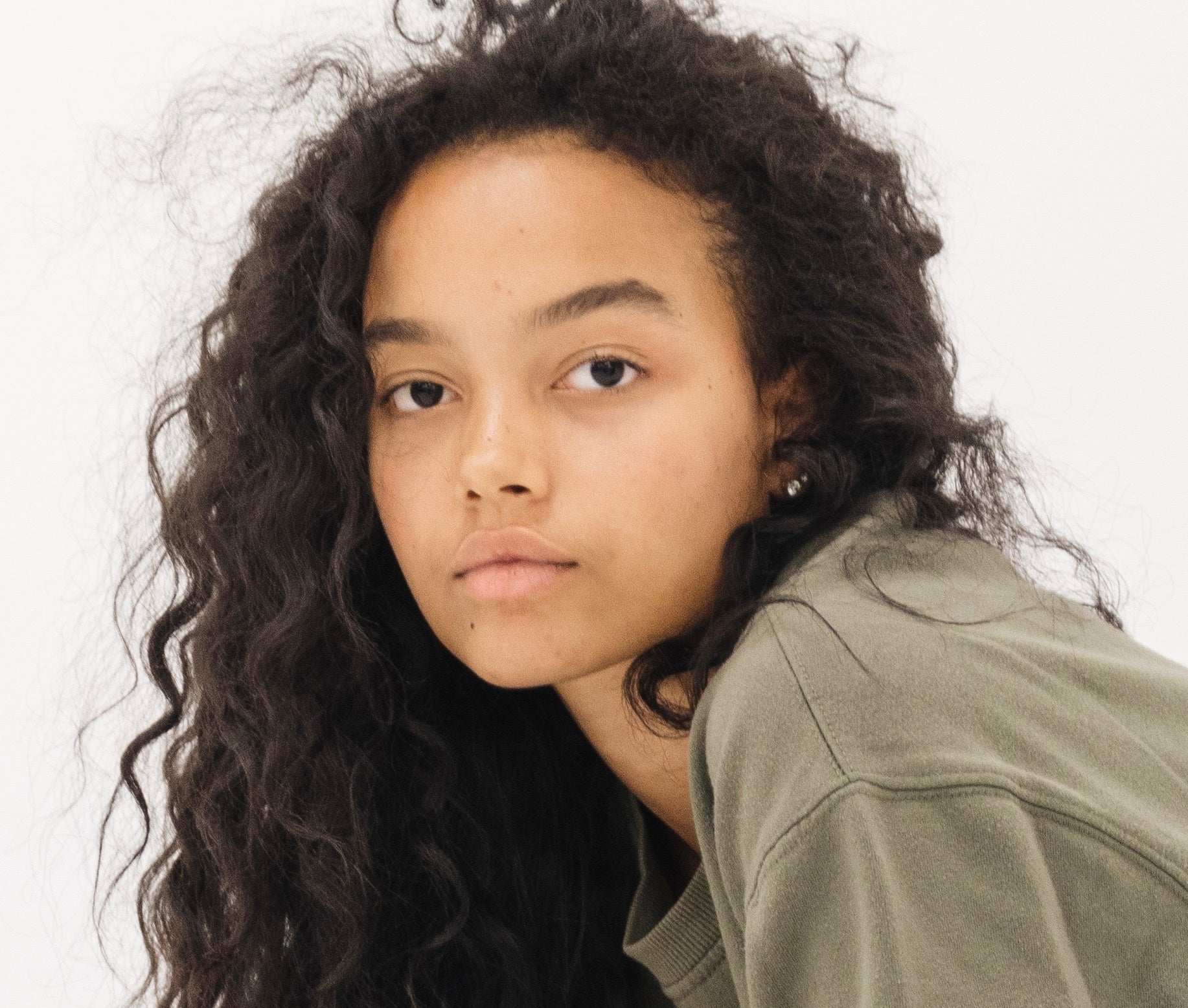 Persona con cabello rizado, mirando a la cámara, usa un suéter de estilo casual