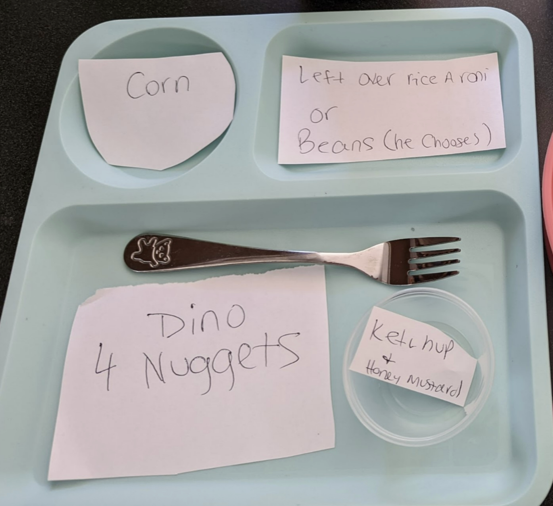 Meal prep for kids with two divided plates: one with corn, meatballs, and a note on peas; another with dino nuggets and a ketchup note
