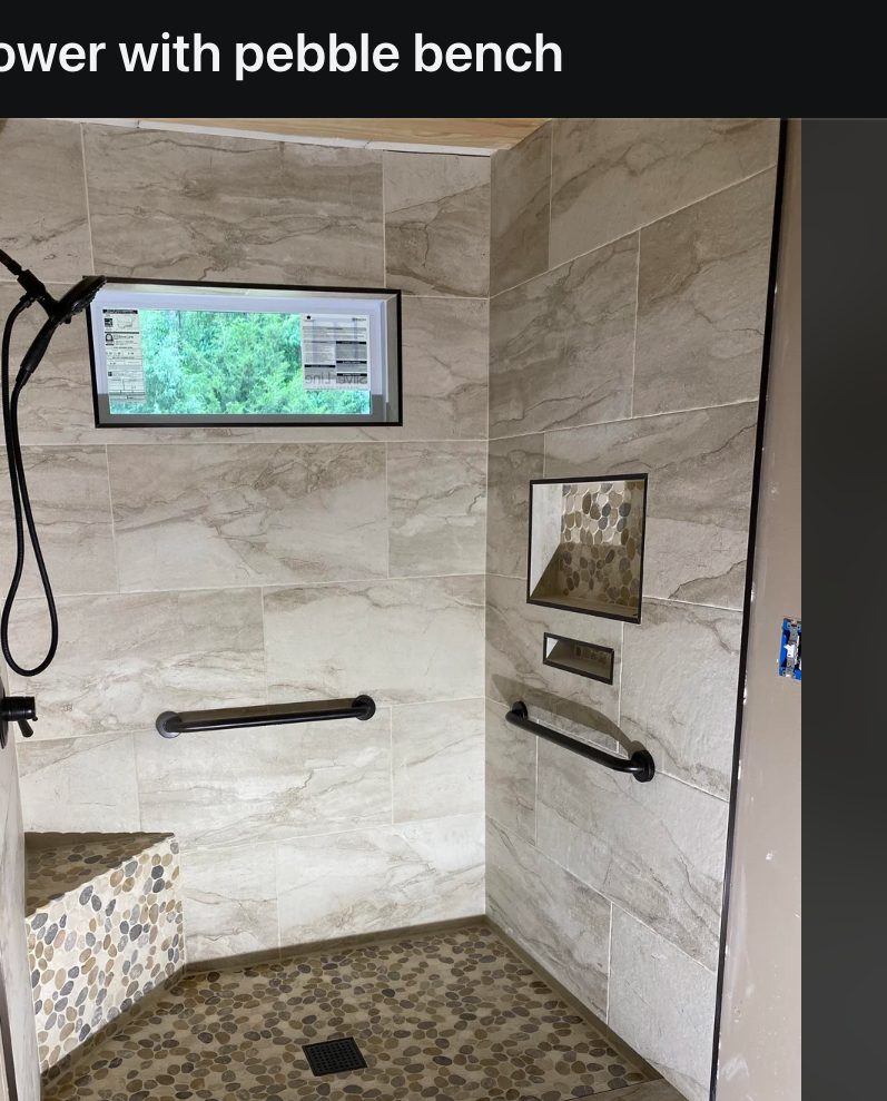 Shower with pebble bench, glass door, wall niche, and modern fixtures in a completed bathroom renovation shared on a social media platform