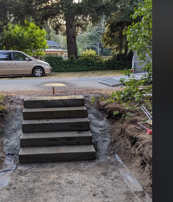 A garden area with a concrete path and a car parked on the street, viewed through a smartphone screen displaying a Reddit post