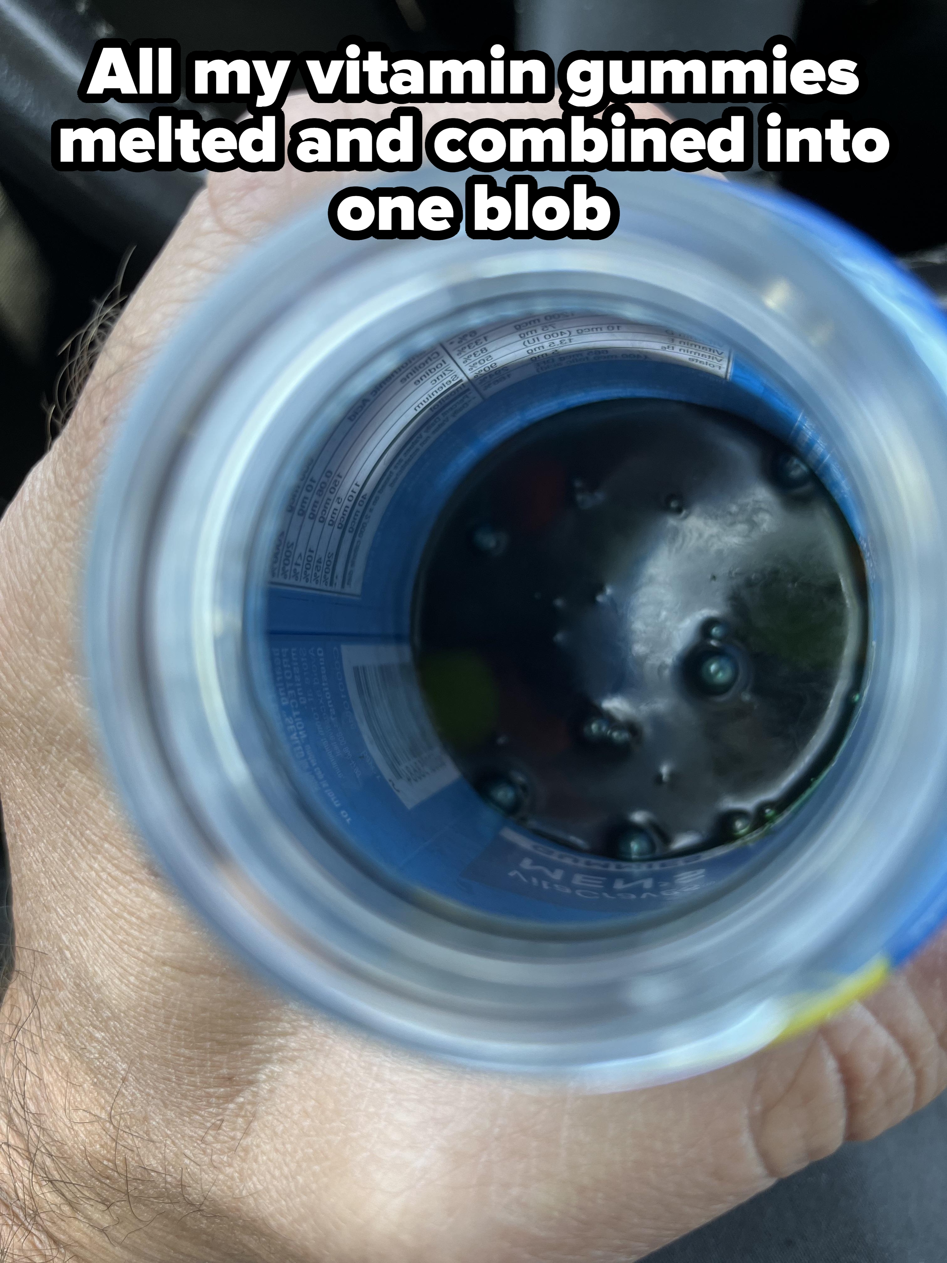 Top-down view of a hand holding a bottle with dark liquid and visible nutrition label inside