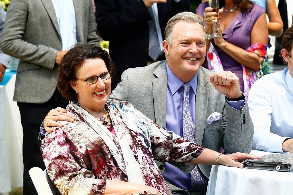 Phyllis and Bob Vance sitting at a table smiling during a scene from The Office