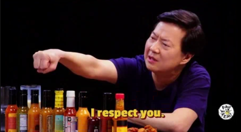 Person extends fist with various hot sauces on table, caption reads "I respect you."