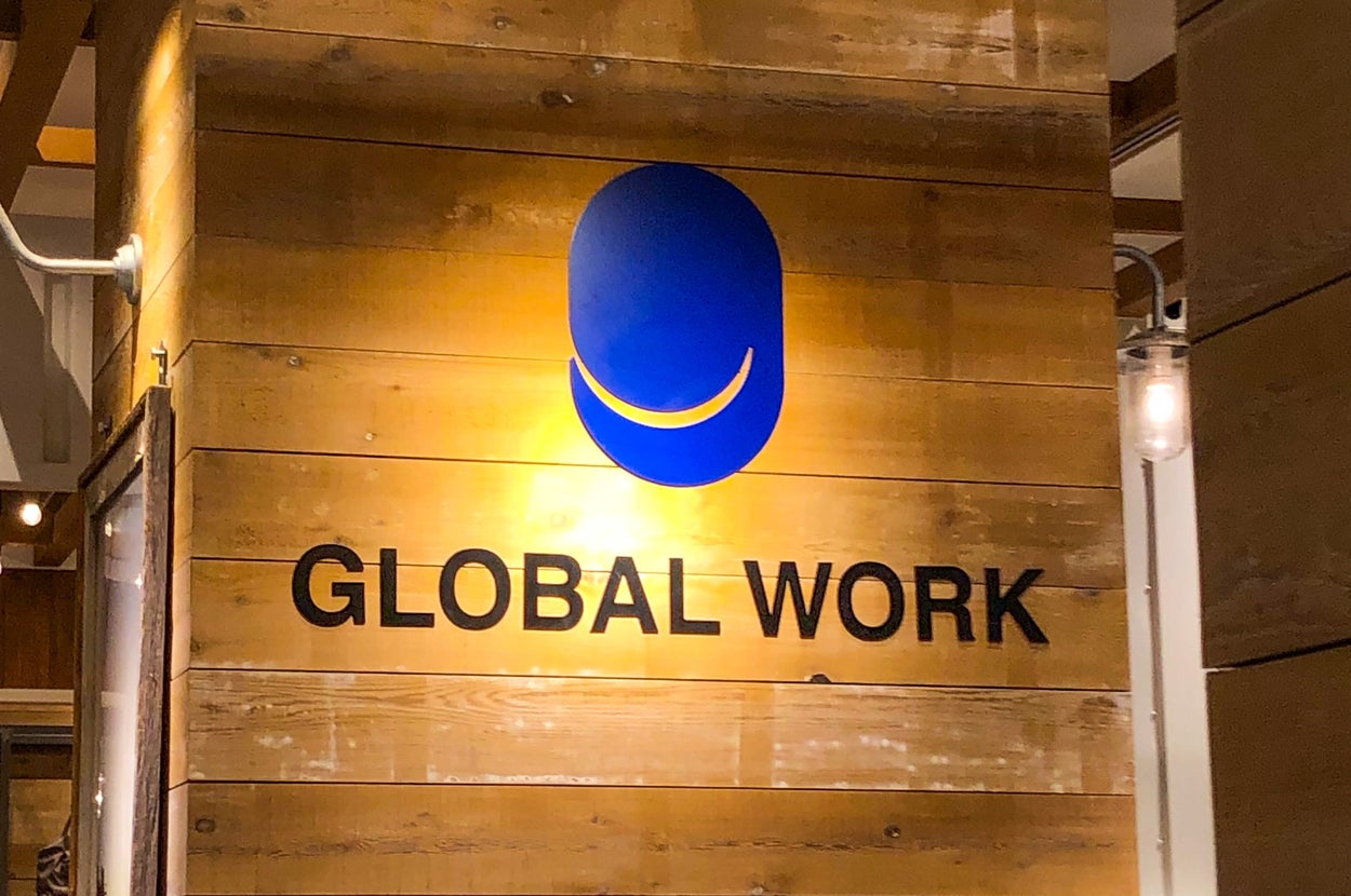 木製の背景に「GLOBAL WORK」と描かれた看板。