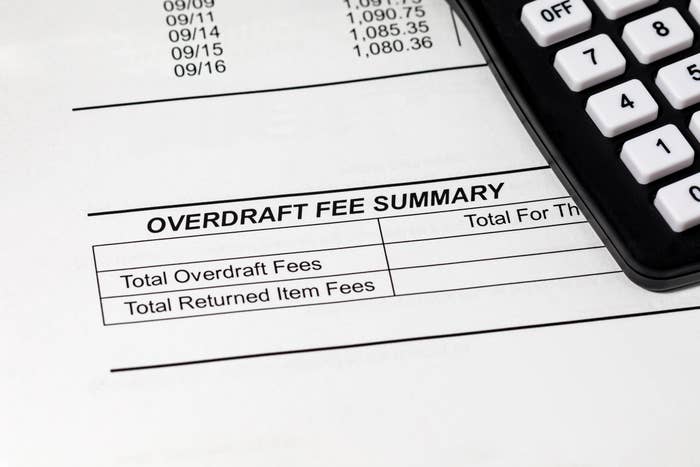 Calculator on paper labeled "Overdraft Fee Summary" with columns for overdraft and returned item fees