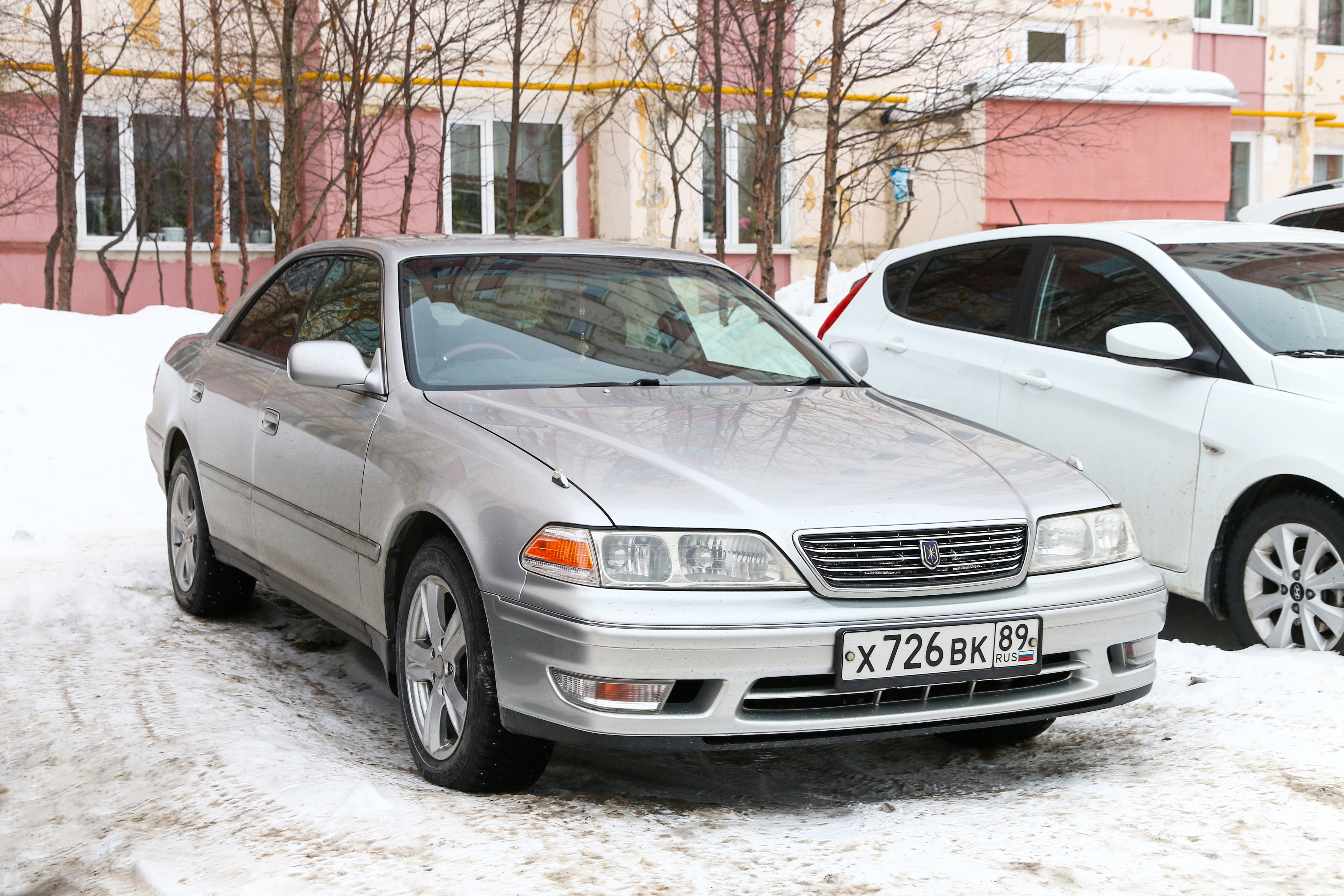 Sedan car parked on a snowy street with a building in the background