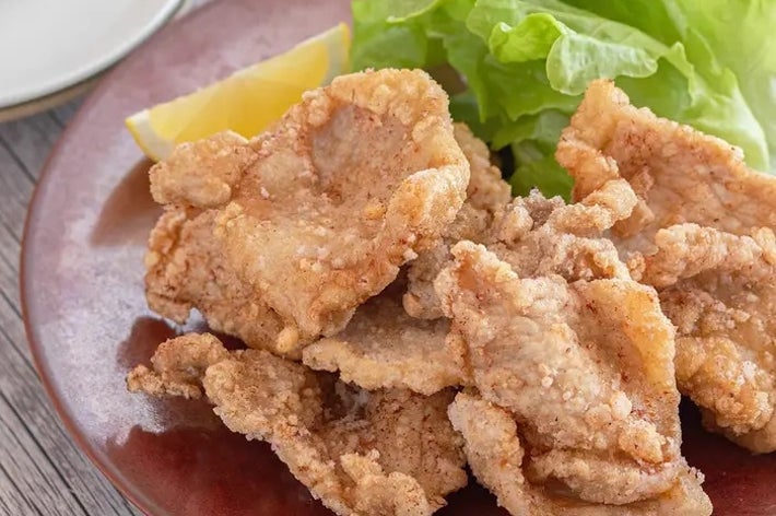 唐揚げがレタスとレモンのスライスと一緒に盛り付けられた木製テーブルの上の皿。
