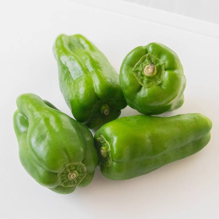 4つの緑のピーマンが白い背景に置かれている。