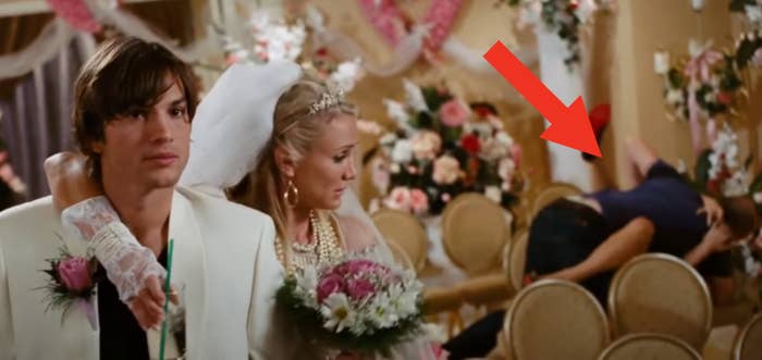 A bride and groom walk down an aisle indoors; the bride holds a bouquet. They are dressed in formal wedding attire