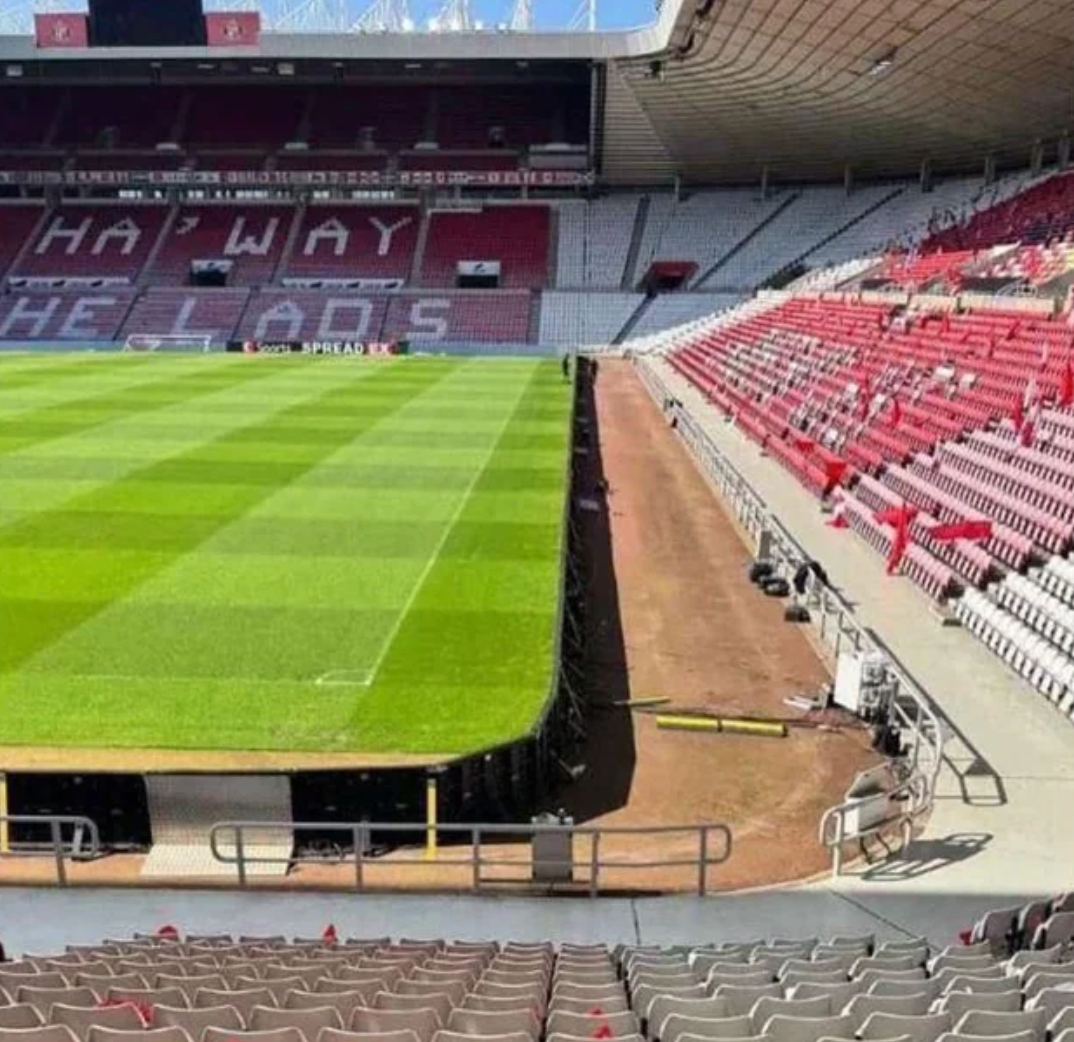 View of an empty stadium with rows of seats and a well-maintained soccer field