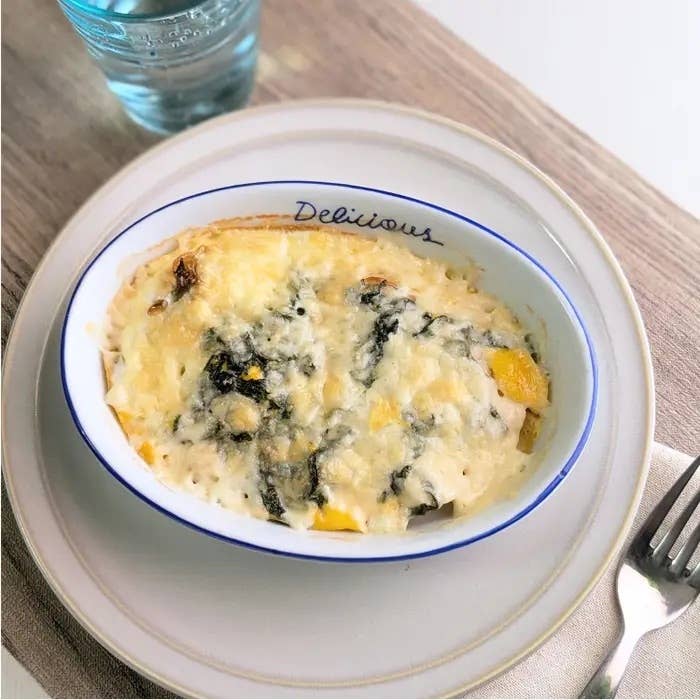 グラタンが皿に盛られ、隣に水のグラスが置かれた食卓の様子。