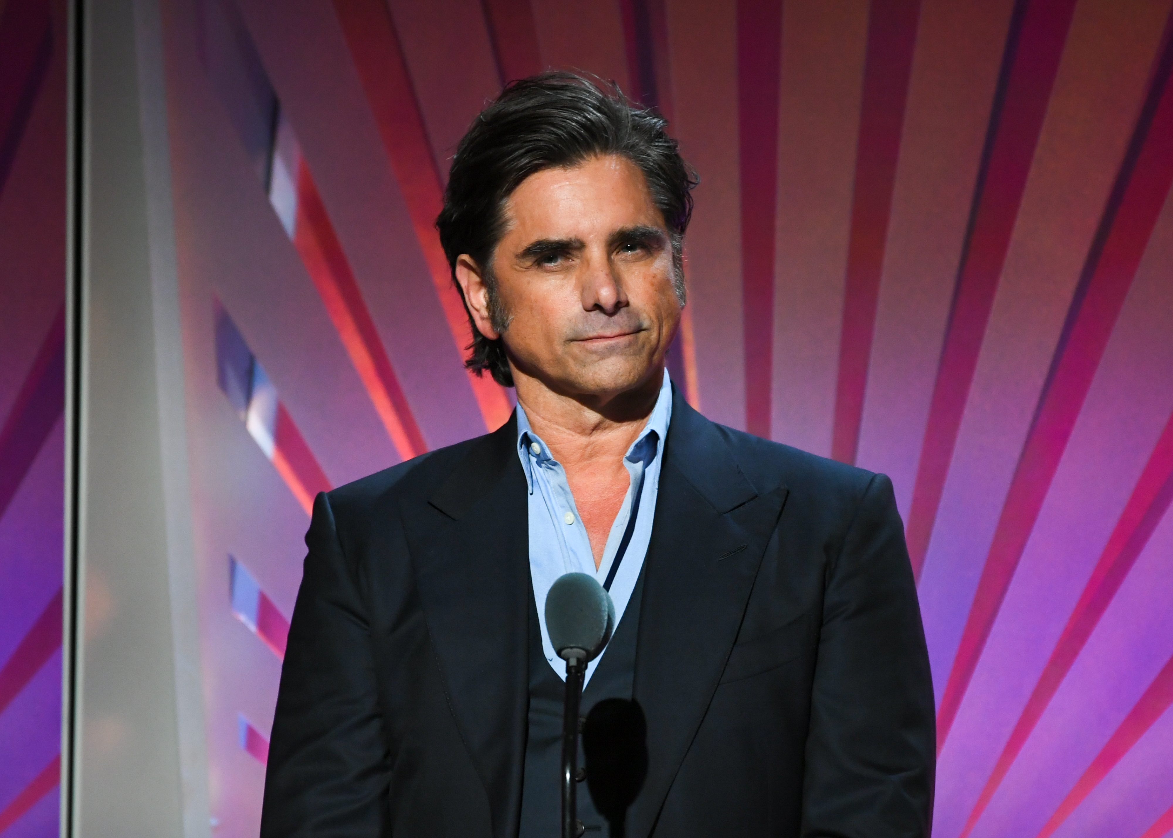 John Stamos standing at a podium