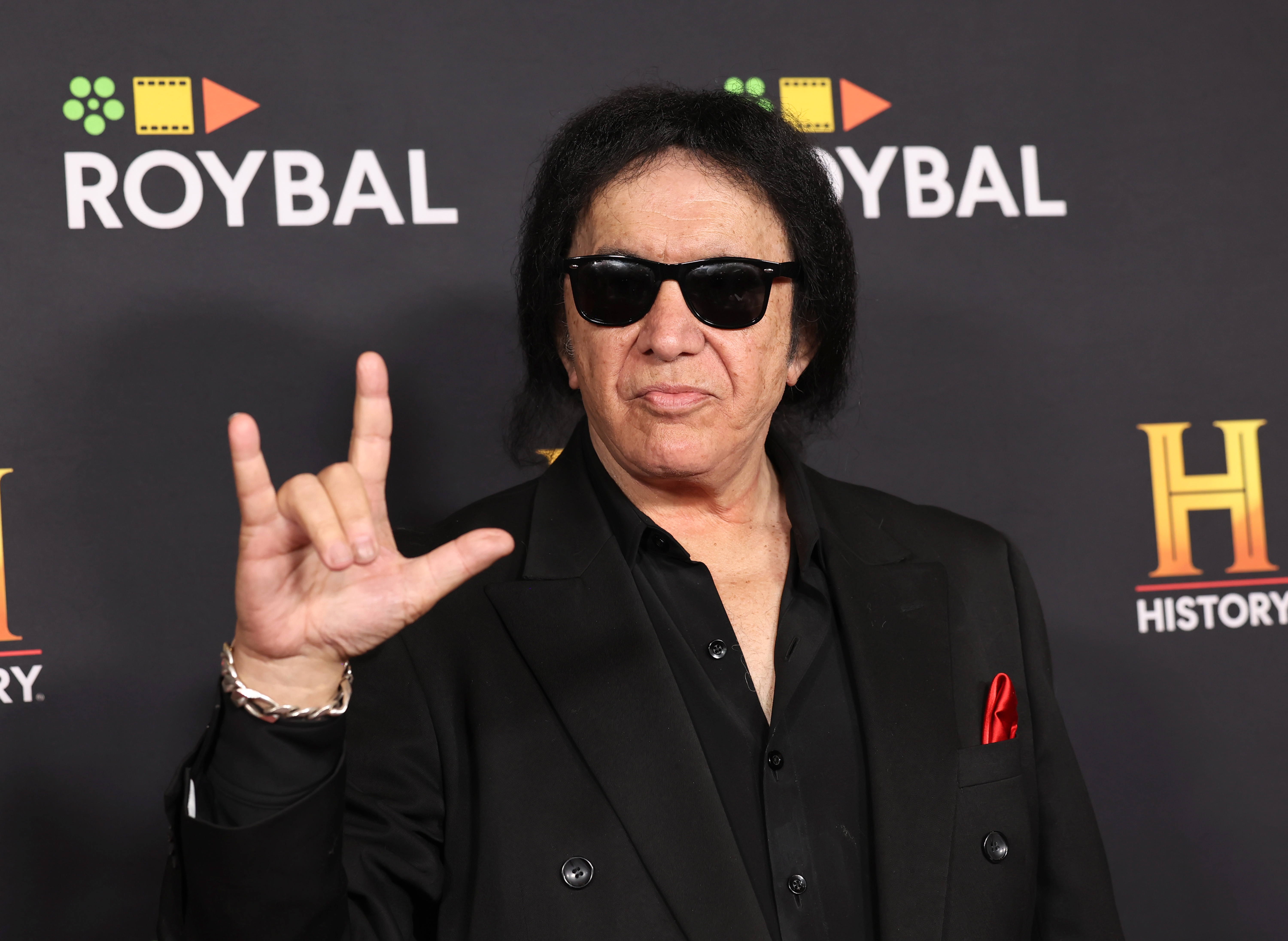 Gene Simmons mkaing a hand gesture on a red carpet at a celebrity event