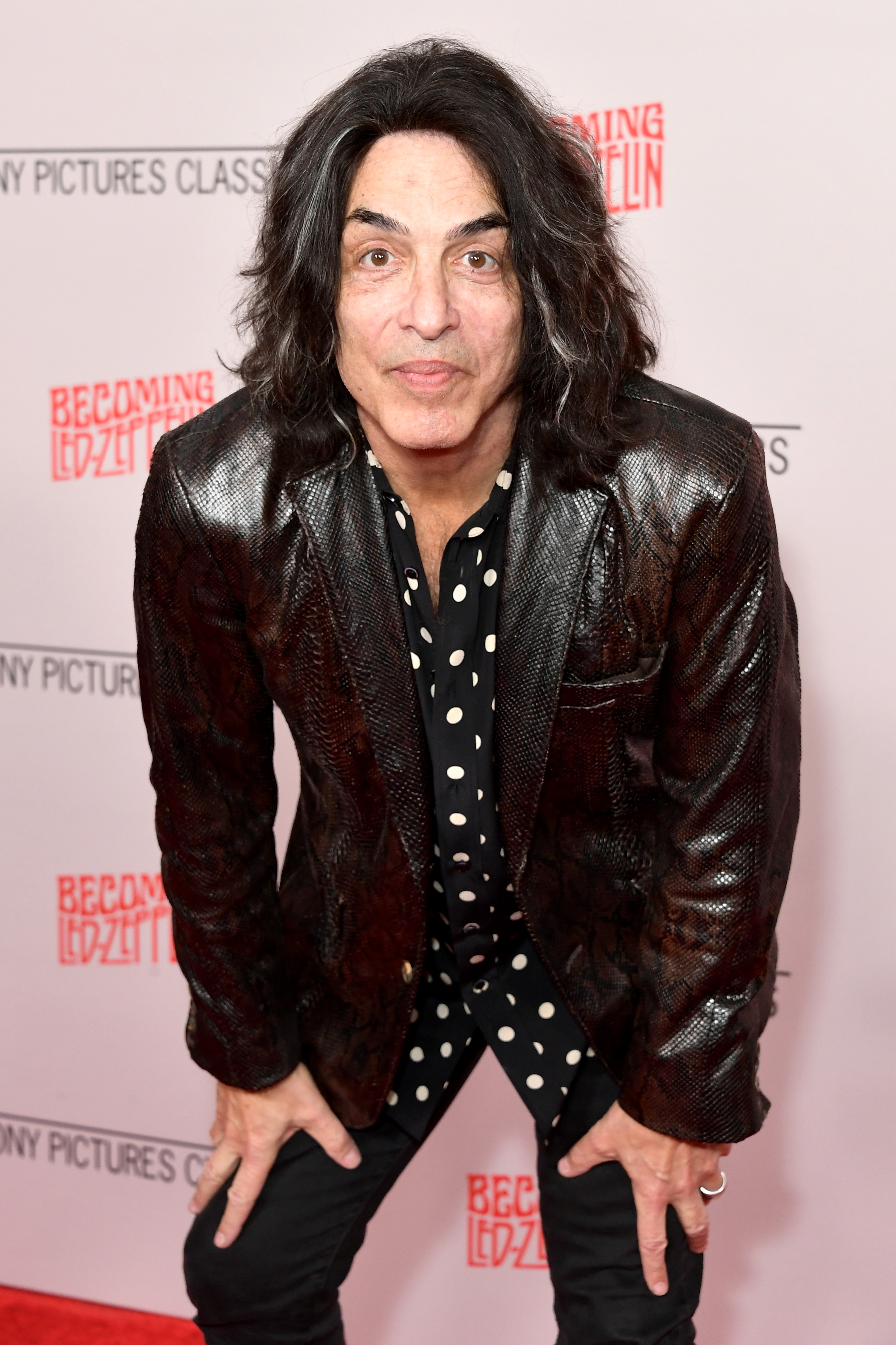 Paul Stanley posing on a red carpet, leaning forward slightly