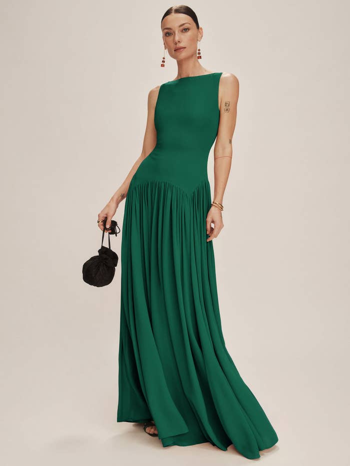 Person poses successful  sleeveless, floor-length gown with pleated skirt successful  emerald green