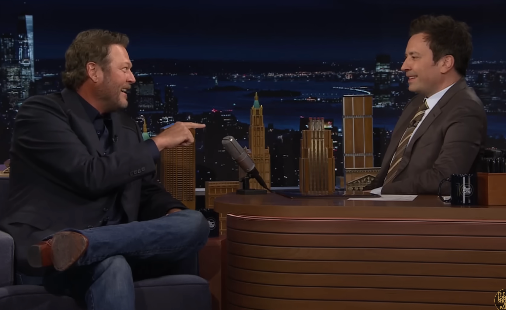 Blake Shelton pointing at Jimmy Fallon sit while speaking on "The Tonight Show"