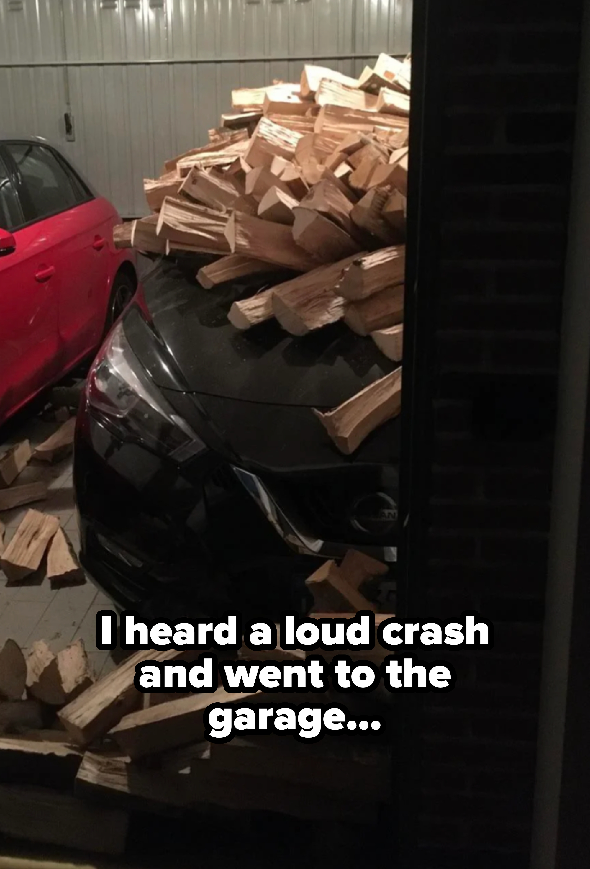 Car partially buried under a large pile of chopped firewood in a garage