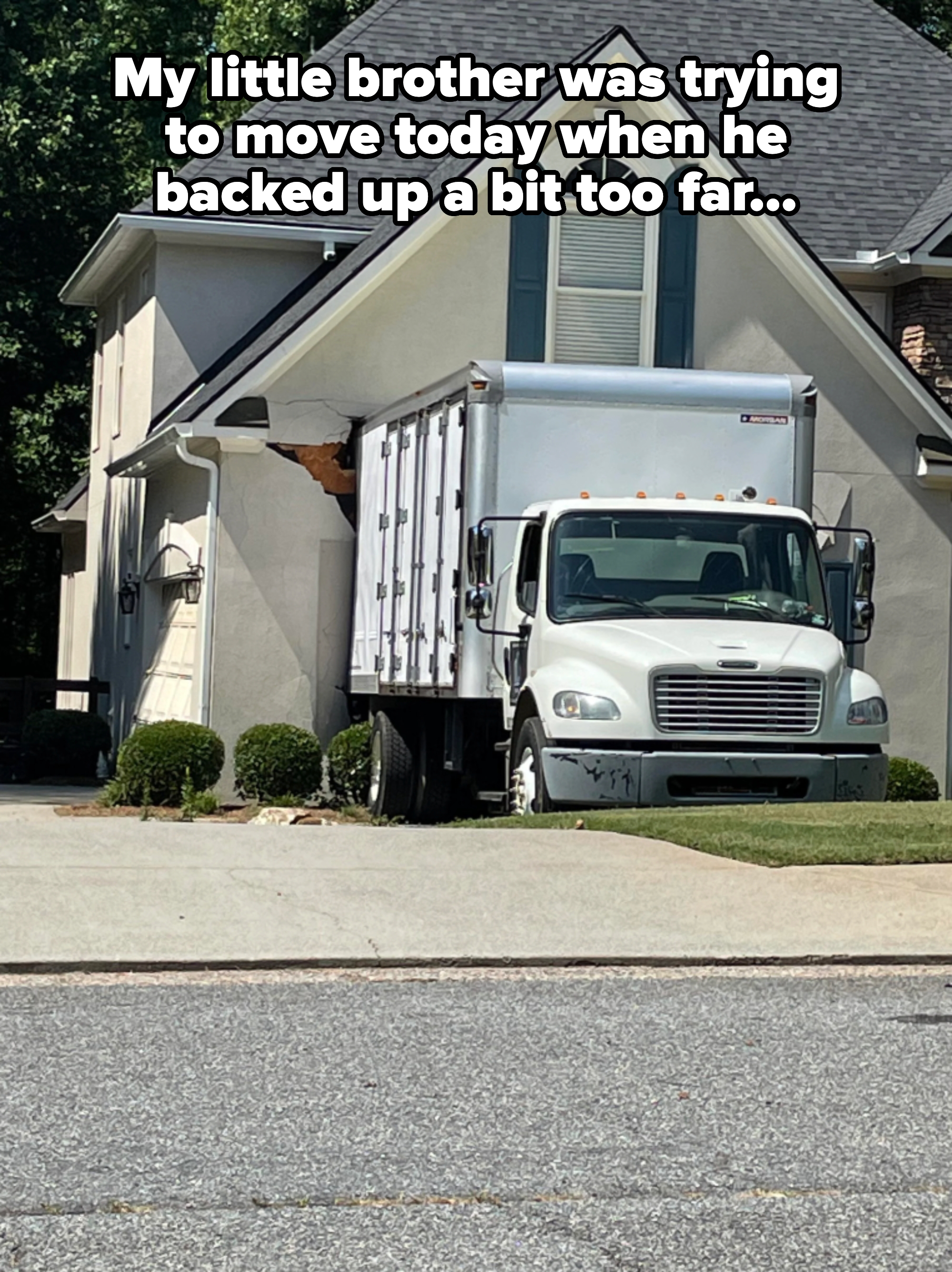 A delivery truck is accidentally lodged into the side of a house, causing visible damage to the building's exterior