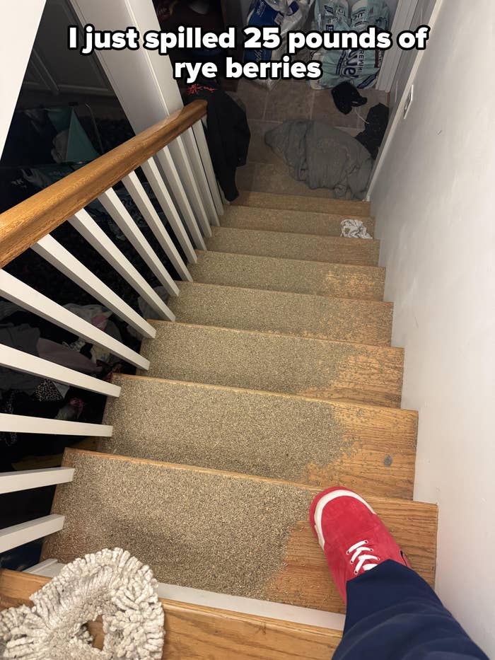 Person wearing red shoes standing at the top of cluttered carpeted stairs, clothes scattered below