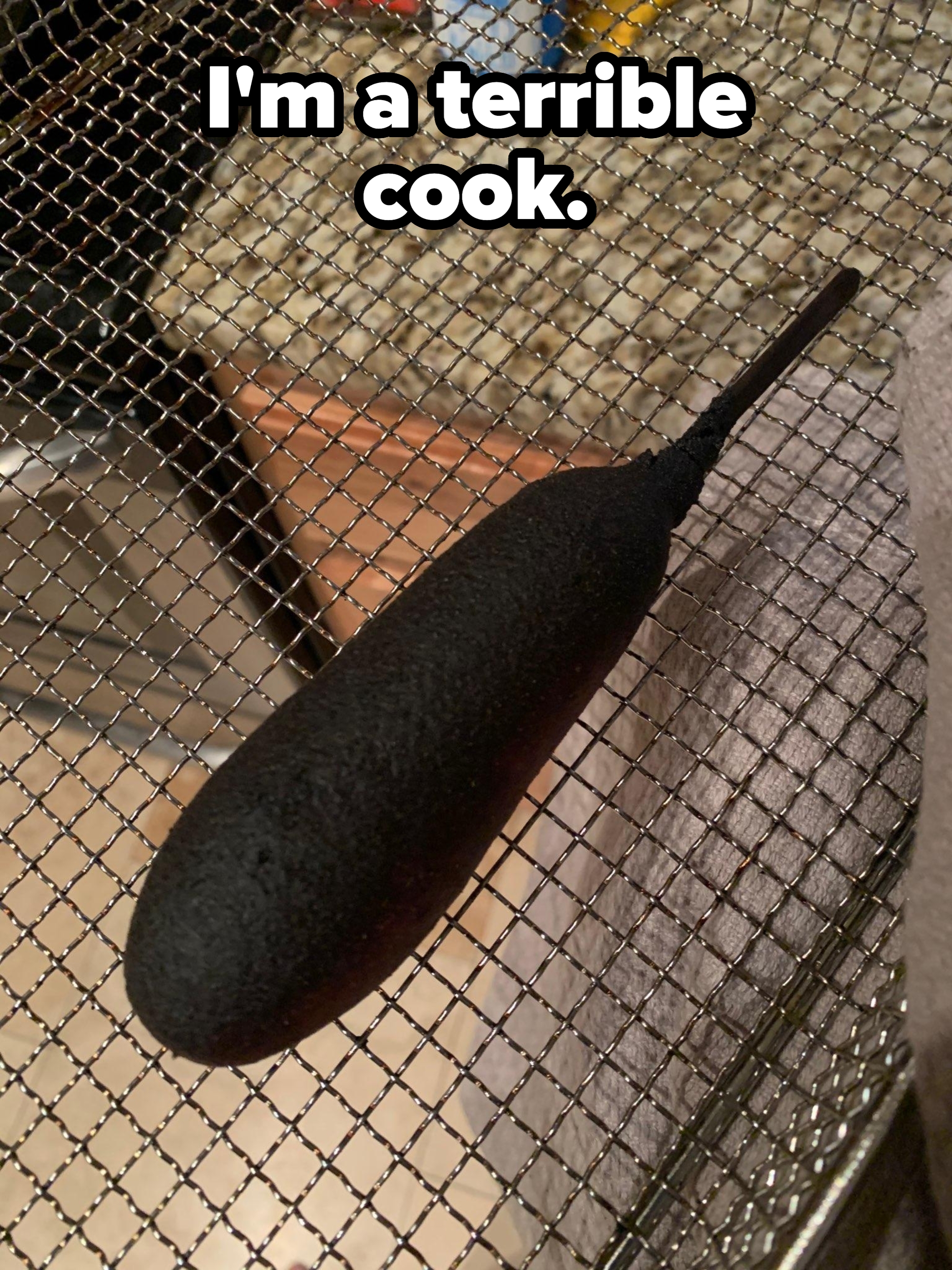 A burnt corndog rests on a cooling rack in a kitchen setting