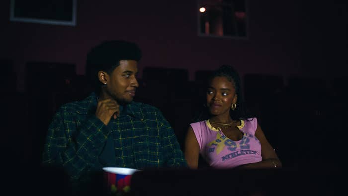 Two radical   sitting successful  a dimly lit theater, conversing and smiling