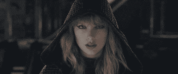 A person in a hooded outfit looks intensely forward, with dynamic camera movements enhancing the dramatic effect