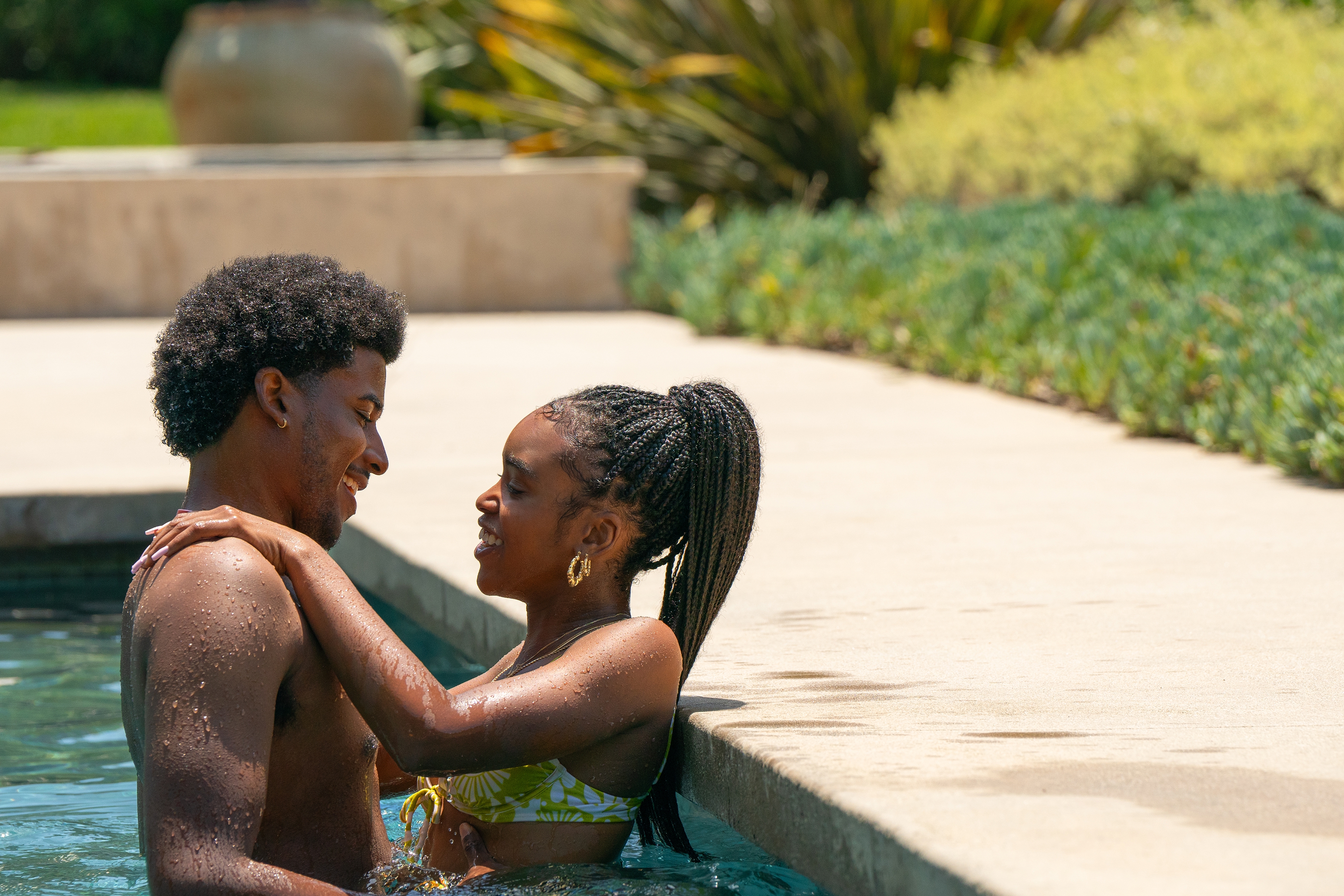Two people smile at each other while enjoying a swim in a pool, creating a relaxed and joyful atmosphere