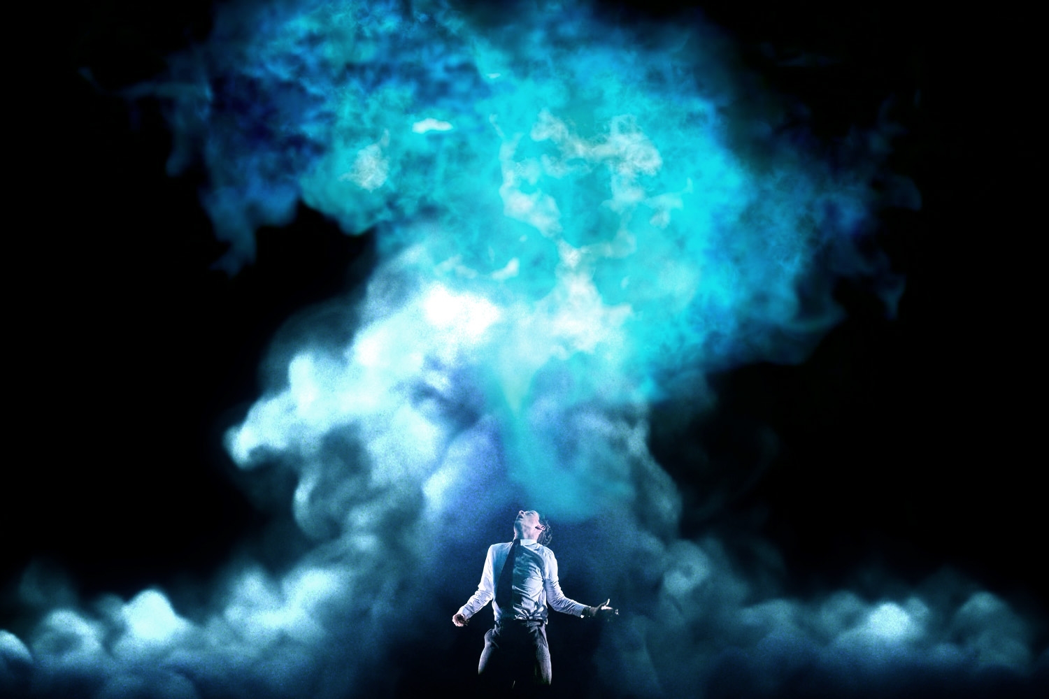 A person on stage dramatically poses amid swirling smoke and light effects, suggesting a powerful or emotional performance