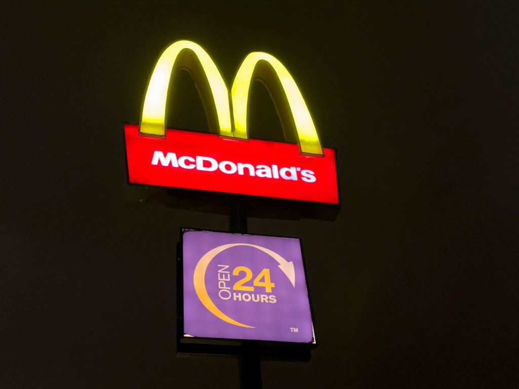 McDonald's sign at night with glowing arches and "Open 24 Hours" text below