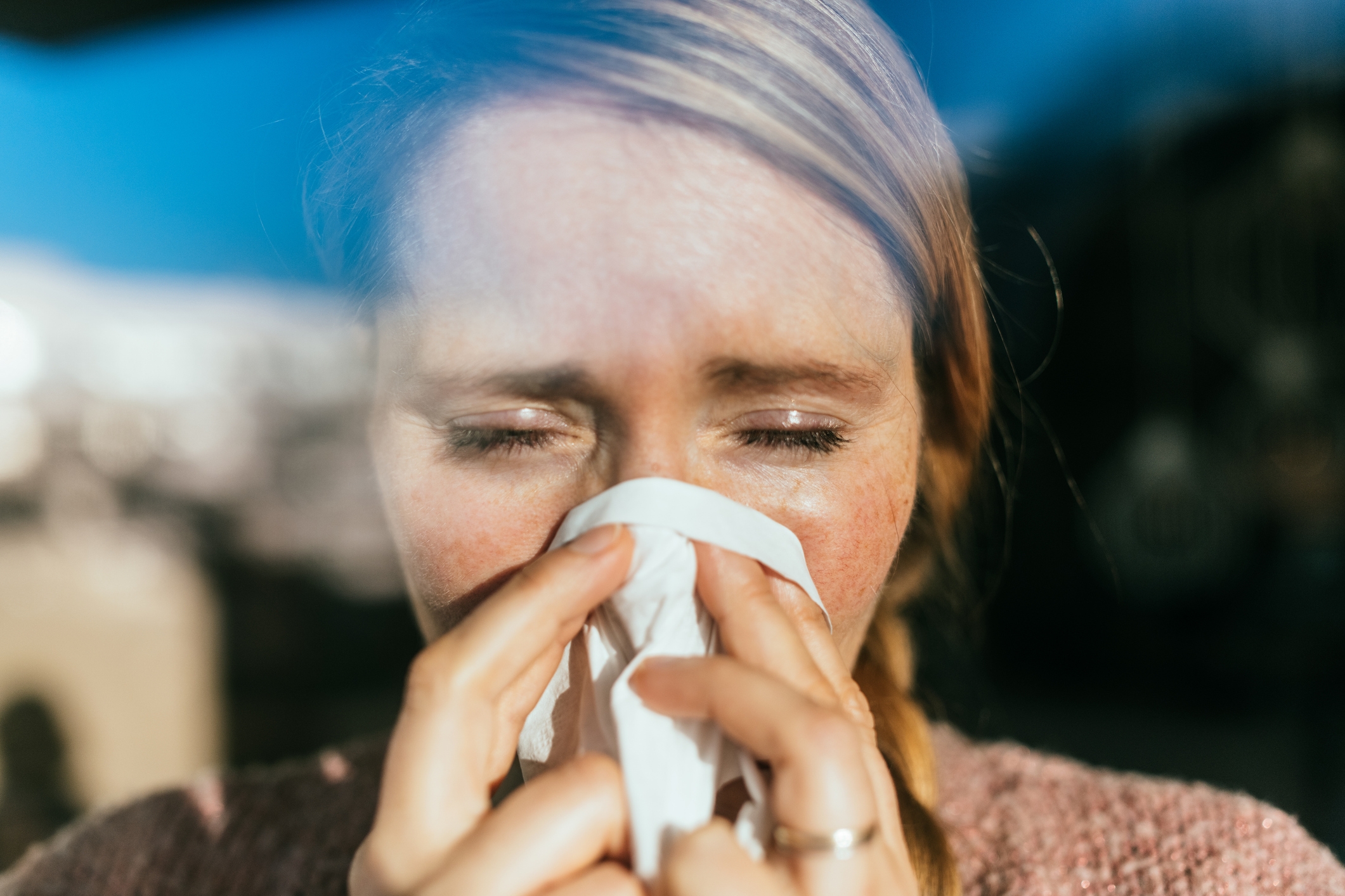 Personen som nyser inn i et vev, lukkede øyne, antyder kulde eller allergier