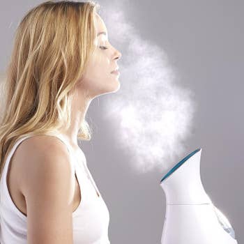 A exemplary uses a facial steamer, eyes closed, enjoying spa-like attraction astatine home