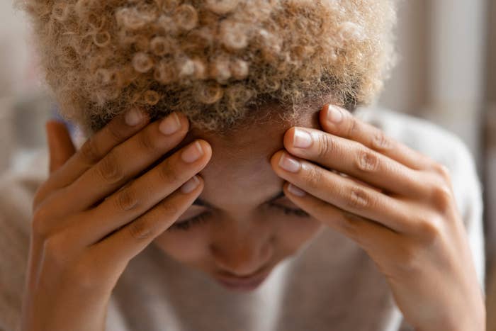 Person holding head with both hands, appearing stressed or in discomfort