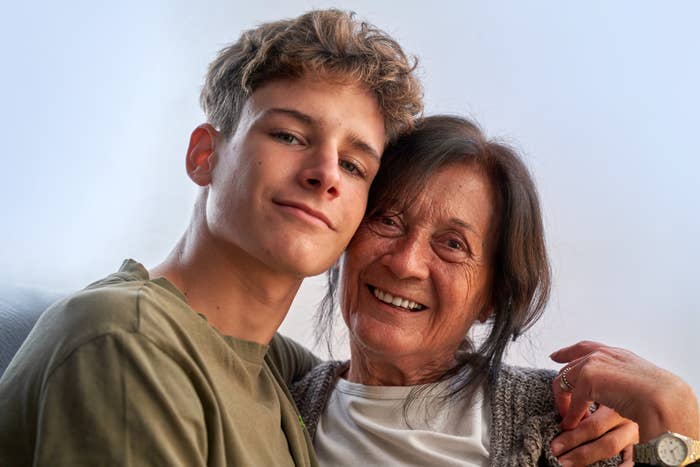 A young man and an elderly woman smiling together, embracing warmly in a candid moment