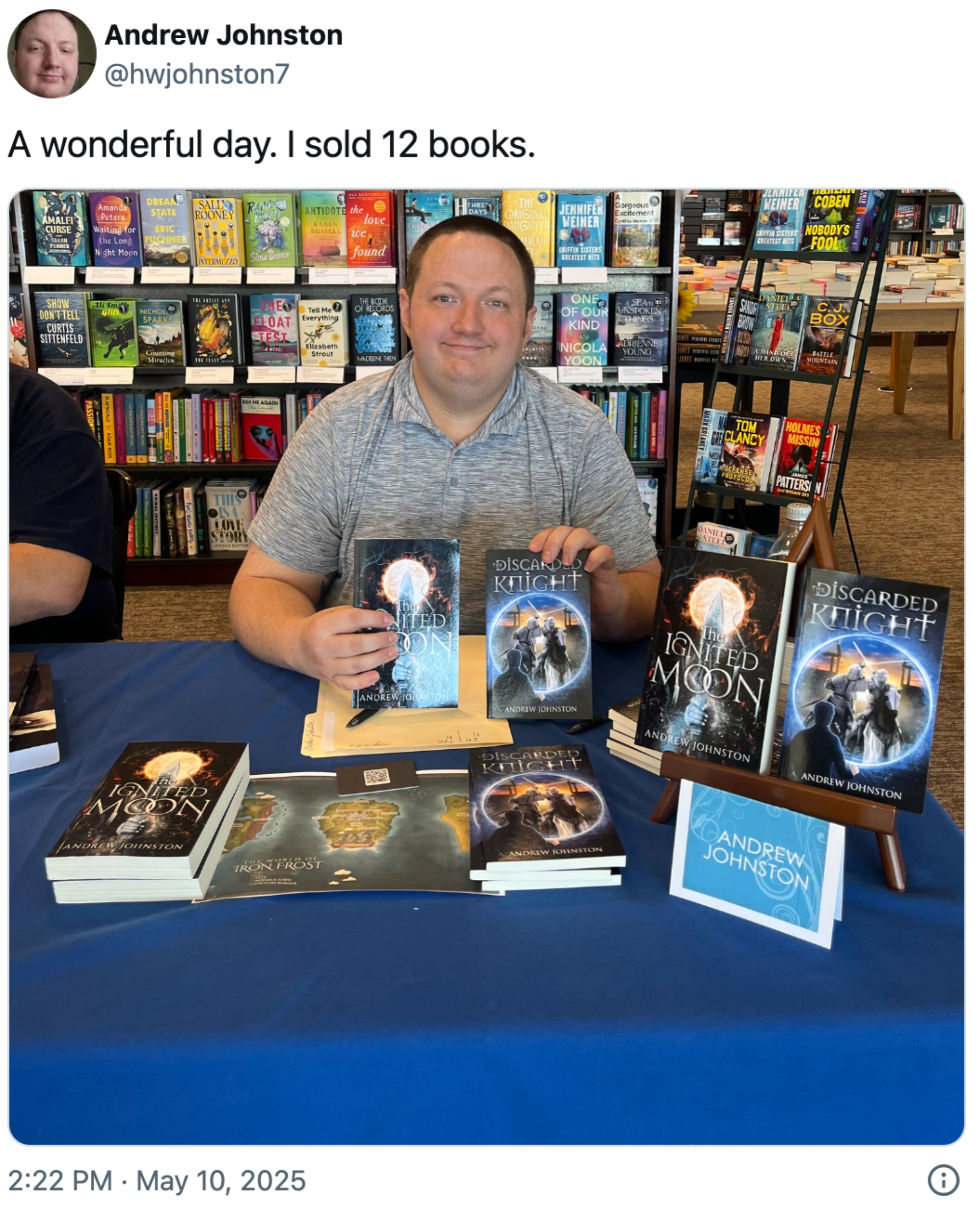 A person sits at a book signing table with fantasy novels, surrounded by bookshelves. Text reads: "A wonderful day. I sold 12 books."