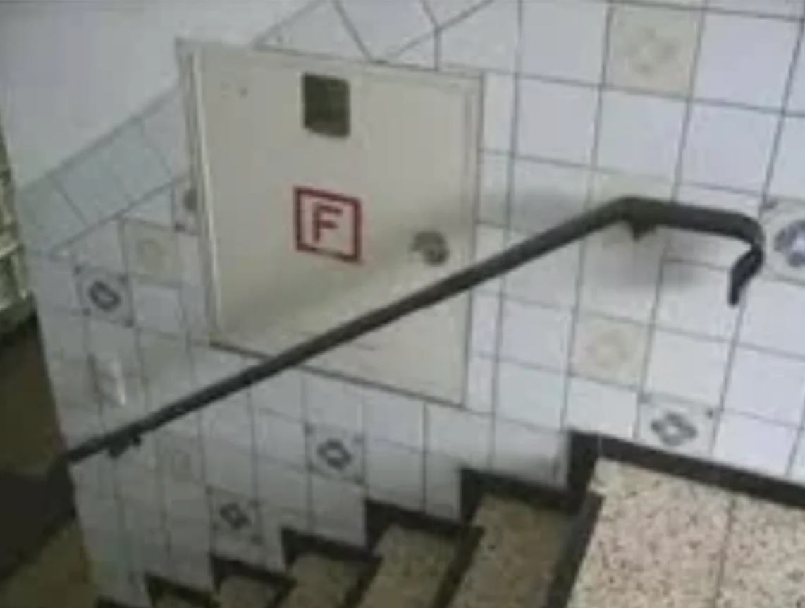 Tile-lined stairtreads ending abruptly against a wall, highlighting an unusable handrail for accessibility and safety awareness
