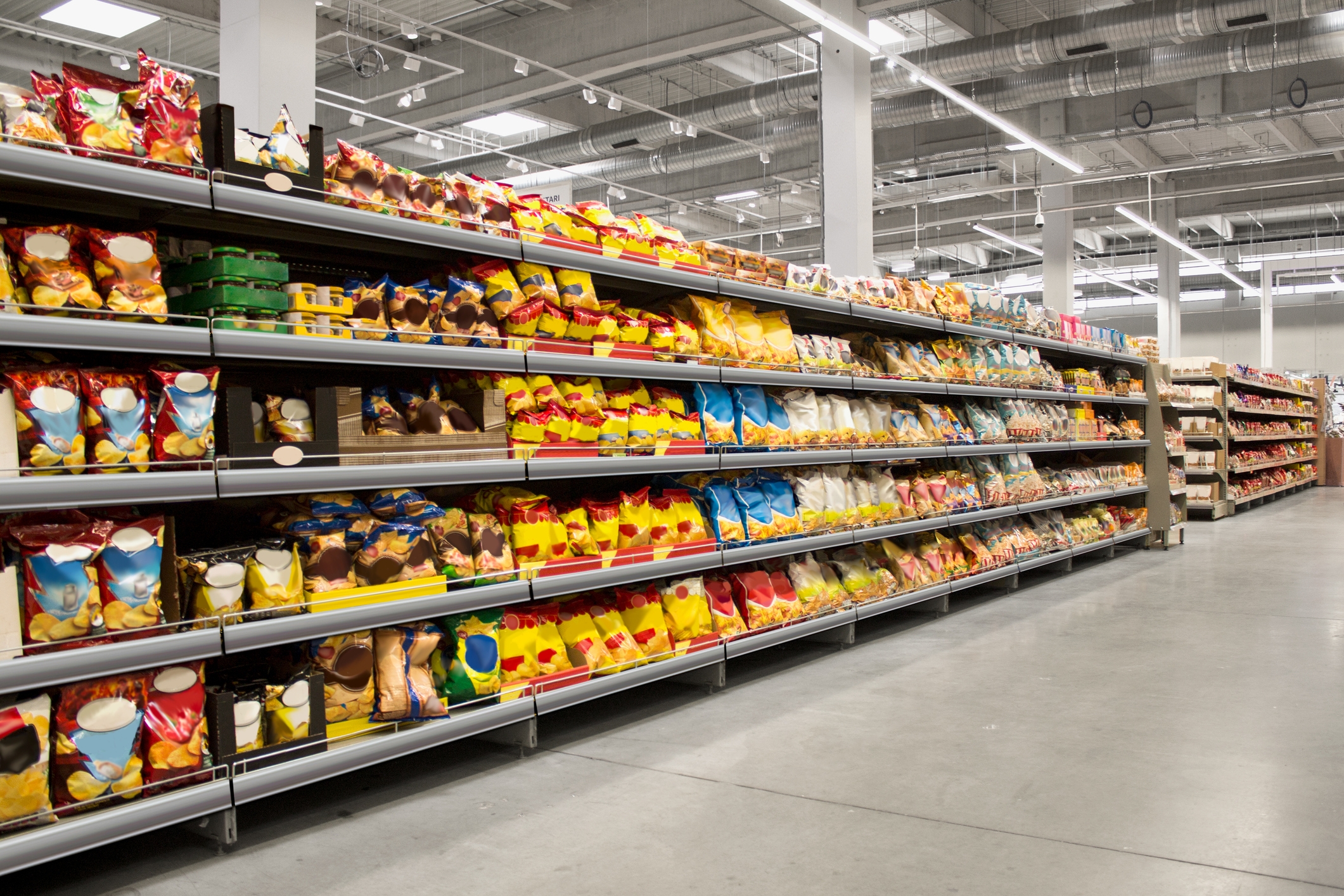 A grocery store aisle filled with various packaged snacks and food items on well-organized shelves